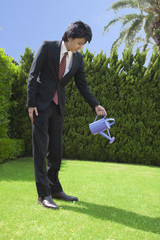 ジョウロで水やりをするビジネスマン