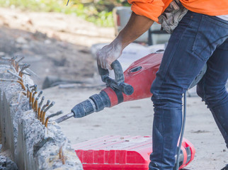 Workers use a jackhammer to break concrete.