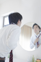 鏡の前でネクタイを締める男性