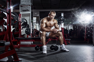 Fototapeta na wymiar bodybuilder athletic guy relaxing after workout in gym