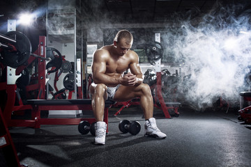 bodybuilder athletic guy relaxing after workout in gym