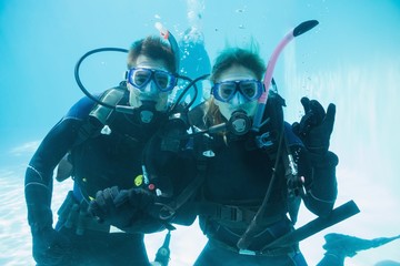 Friends on scuba training submerged in swimming pool looking to