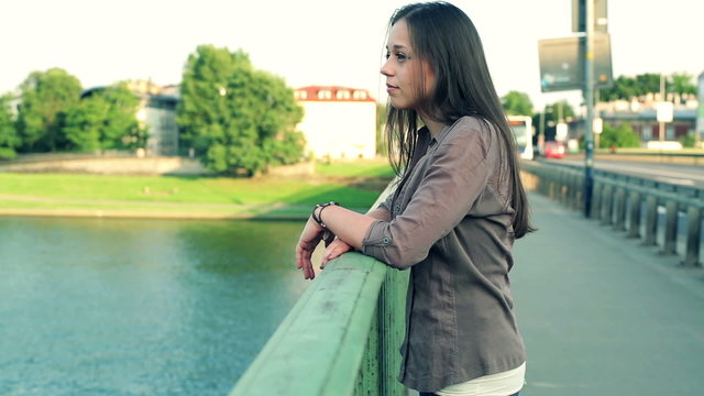 Sad beautiful woman looking at river in the city