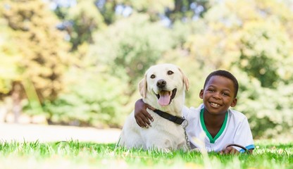 Cute afro american little boy lying with labrador dog