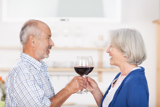 glückliches seniorenpaar stößt mit rotwein an