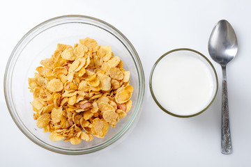 bowl of cold cereal, glass of milk and spoon on white background