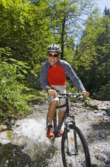 Fototapeta na wymiar Mountainbiker fährt durchs Wasser