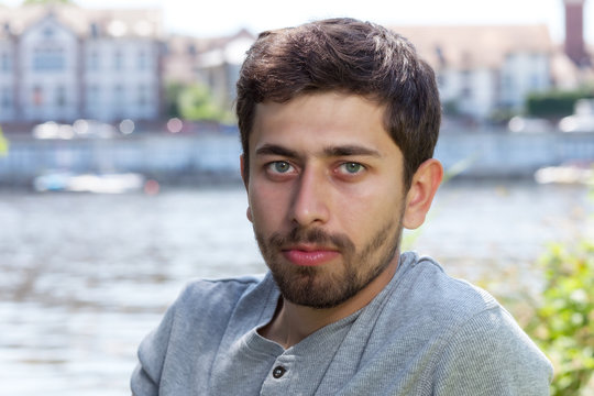 Smiling man with beard in a grey shirt on a river