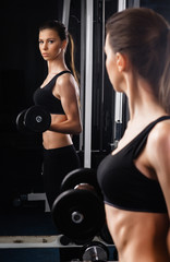 Fototapeta na wymiar Beautiful young woman during fitness with dumbbells.