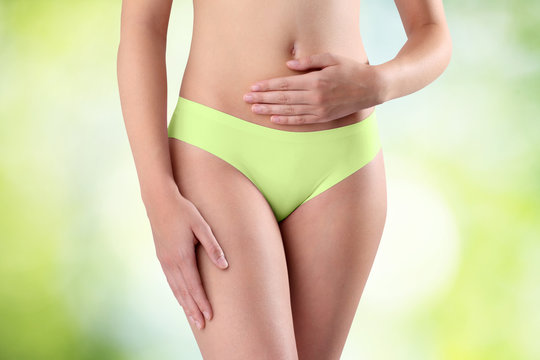Woman's hands on stomach on green background
