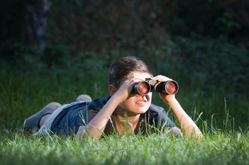 boy lying in grass with binocular