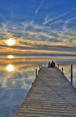 Fototapeta na wymiar sentados en el embarcadero mirando la puesta de sol