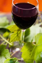 Fotobehang Red wine in glass with grape leaves © Maksim Shebeko