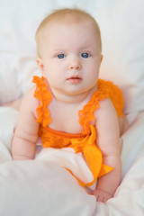 Blond baby girl with blue eyes in a romper