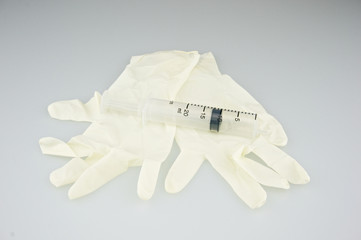 Big plastic syringe place on latex gloves