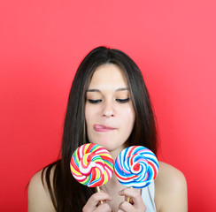 Portrait of woman holidng lollipops against red background