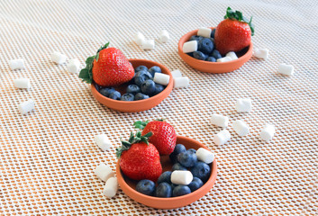 Berries, marshmallows in small clay dishes
