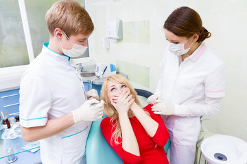 Fototapeta premium Female patient in dentist office afraid of doctor, procedure