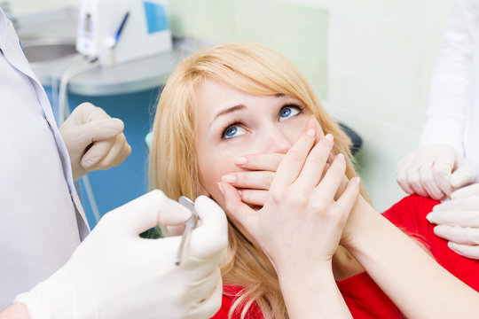 Female patient in dentist office afraid of doctor, dentist