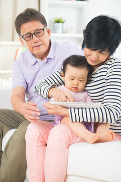 asian grand parents teaching grand son internet with a tablet