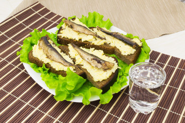 Sprats on bread with garlic cheese and a glass of vodka