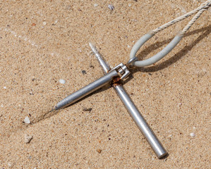 Obraz premium Metal anchor with rope fixed in the sand at seashore