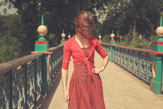 Woman wearing a red dress on bridge in a park