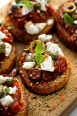 Crostini with roasted tomato sauce, olives, capers and herbs