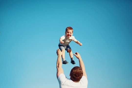 Happy joyful child, father fun throws up son in the air