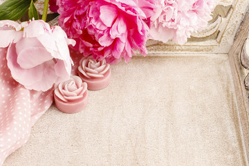 Pink peonies and scented candles on wooden tray