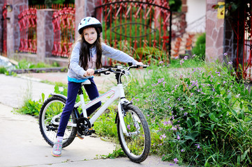 Fototapeta premium Adorable kid girl in blue helmet riding her bike 