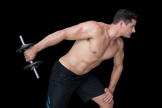 Strong crossfitter lifting heavy black dumbbell behind him