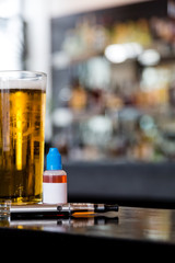 Glass of beer with electronic cigarette and juice