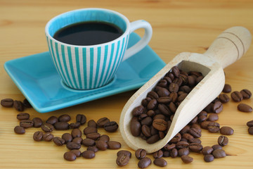 Coffee beans on wooden wooden scoop and coffee in vintage cup