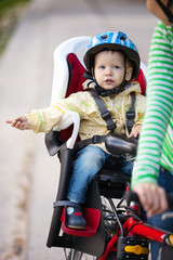 Obraz premium Little boy in the seat bicycle behind mother