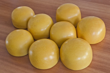 Yellow shiny cow cheese against a wooden background