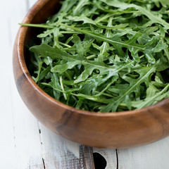 Wooden bowl with arugula lettuce, close-up, studio shot