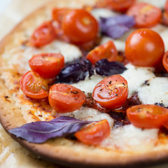 Naklejka na ściany i meble Close-up of pizza with red cherry tomatoes, mozzarella and basil