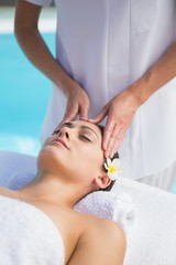 Obraz na płótnie Canvas Tranquil brunette getting a head massage poolside