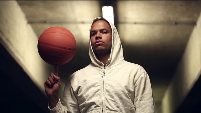 Male hooded basketball player spinning a basketball
