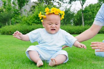 Head wearing a wreath of baby sitting on the grass