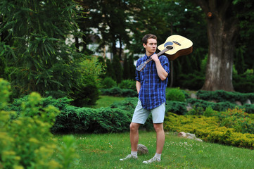 Young man with acoustic guitar in park