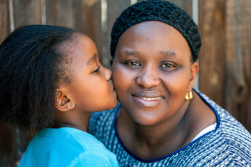 African girl kissing mother on cheek.