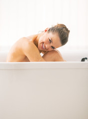 Happy young woman sitting in bathtub