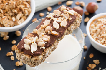 oat bar with chocolate and nuts, a glass of milk, close-up