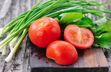 Tomatoes with onions and arugula on a wooden board