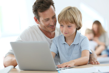 Man with little boy playing on laptop computer