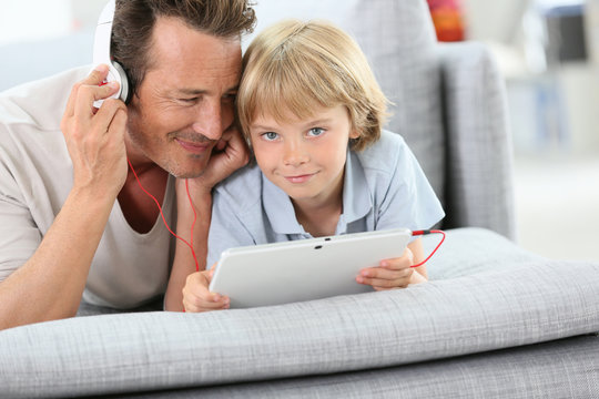 Father and son listening to music on tablet