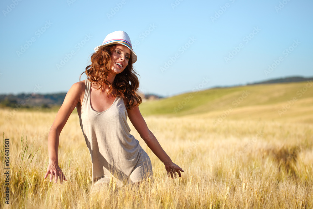 Wall mural young beautiful woman on golden cereal field in summer