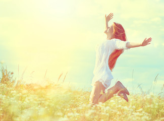 Beauty model girl in white dress jumping on summer field